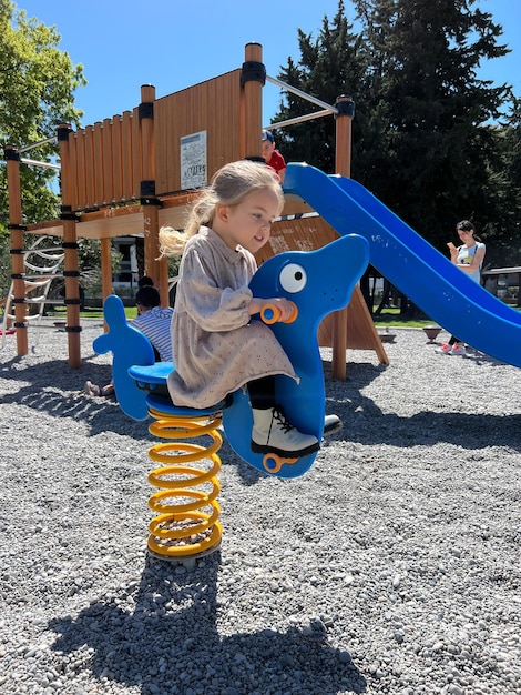 写真 小さな女の子が遊び場でスイングスプリングに乗っています