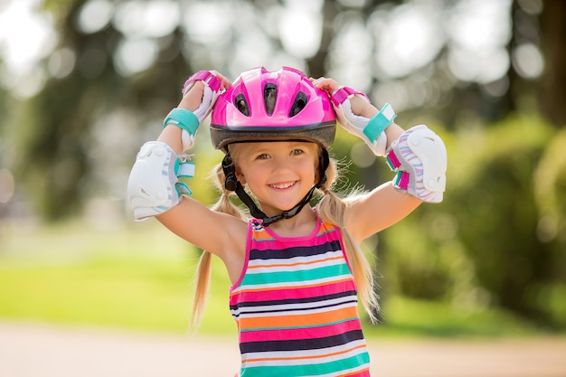 little girl rides on roller skates in the summer in a city Park