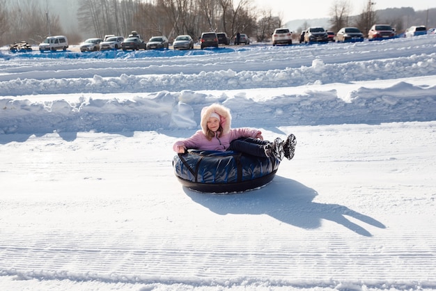 A little girl rides a tubing down a slide