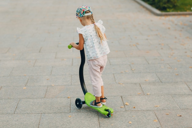 Фото Маленькая девочка на скутере по улице города.