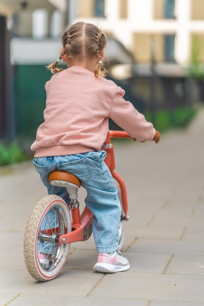 ヨーロッパのプラハの邸宅の中庭でバランスバイクに乗る少女