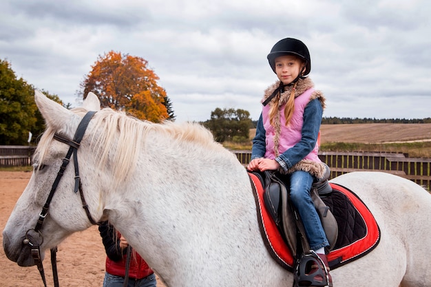 Little girl riding a horse on a farm