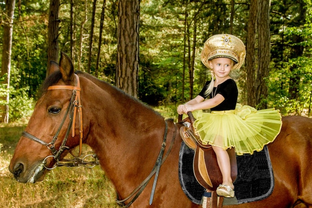 Little girl riding a horse in the forest