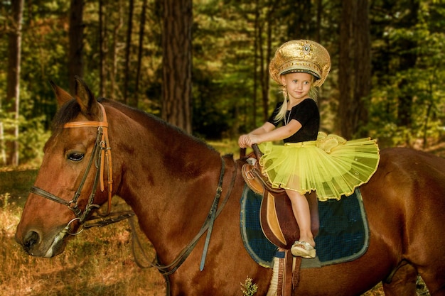 Little girl riding a horse in the forest