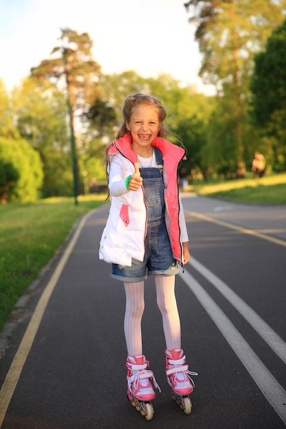 Photo little girl on roller skates makes a gesture thumb up in the park