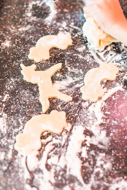 Photo little girl rolling out and cutting out unicorn sugar cookies.