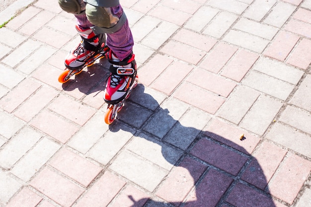 A little girl rolls on red rollers on the sidewalk