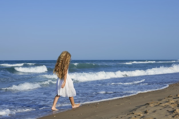 Маленькая девочка работает пляж в синем море