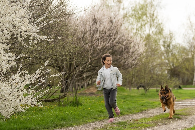 Little girl running with a dog in a flower garden