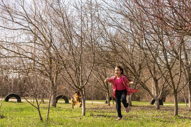 little girl running with his pet german shepherd.