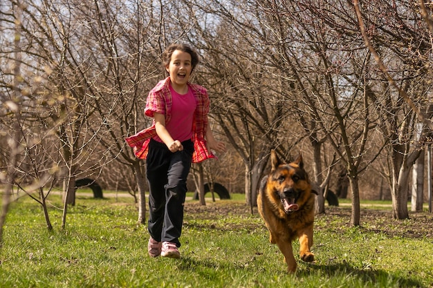 little girl running with his pet german shepherd.