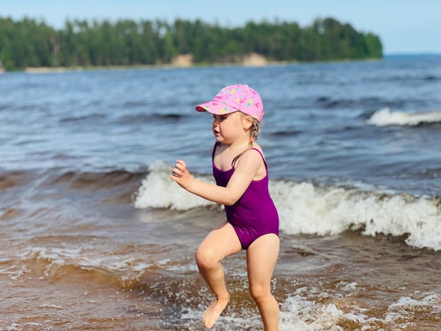 Маленькая девочка бежит с брызгами в море