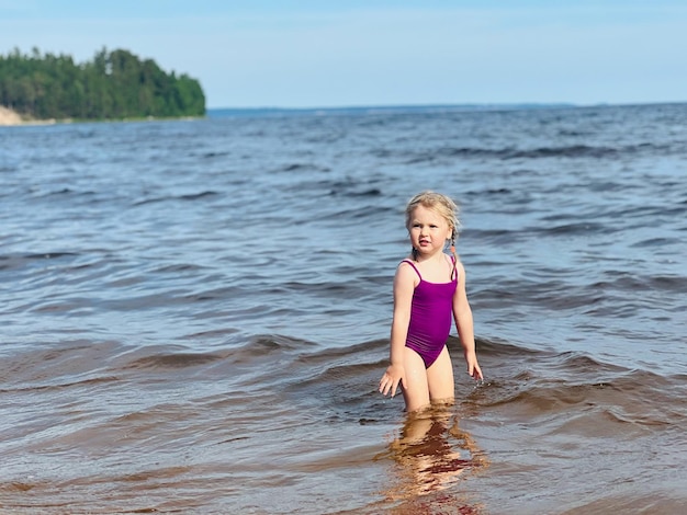 Маленькая девочка бежит с брызгами в море