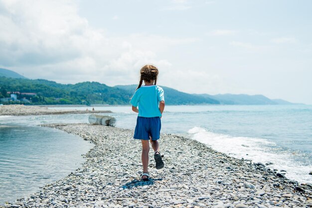 A little girl runs along the beach. Summer.