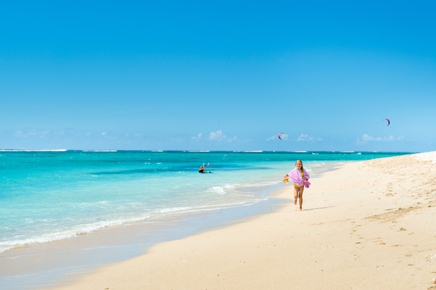 Una bambina corre lungo la spiaggia dell'isola tropicale di mauritius nell'oceano indiano.