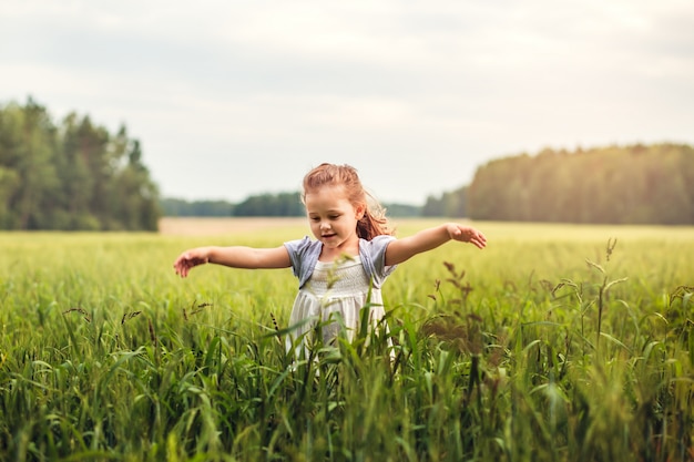 little girl runs in the meadow in summer