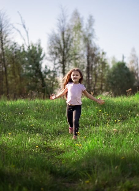 Little girl runs in the meadow in summer