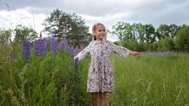 Little girl runs among purple lupines in blooming field health nature summertime happy childhood