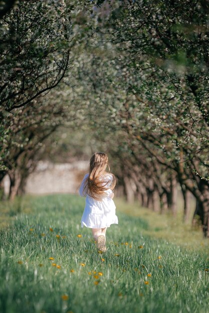 A little girl runs through a blooming garden