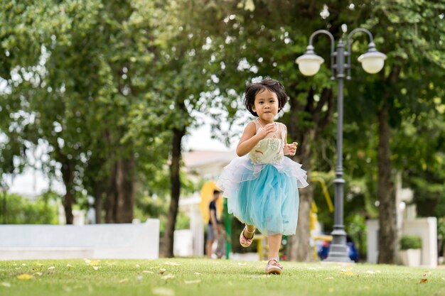 A little girl runs through a park in a blue tutu.