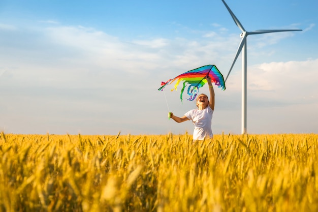 Little girl runs in a wheat field with a kite