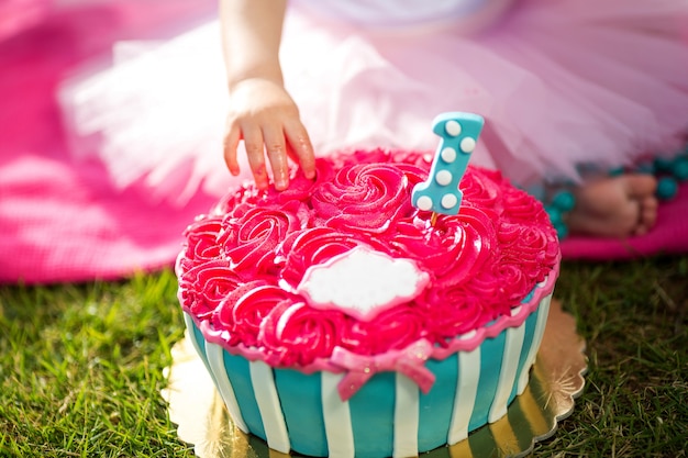 Little girl's hand tastes a beautiful pink flower shaped cake