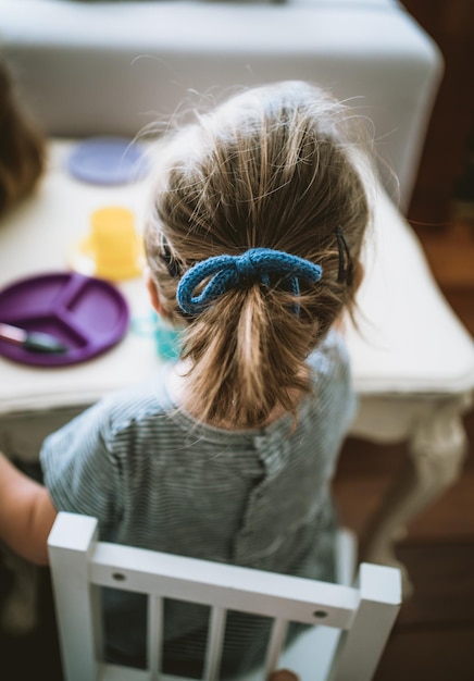 A little girl's ponytail sitting at a dining table