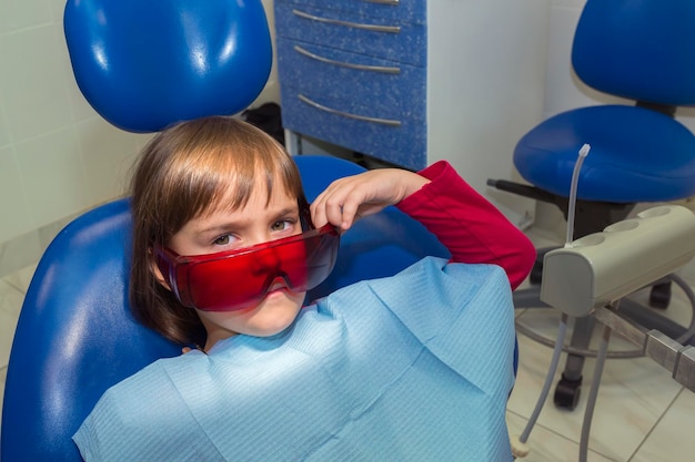 A little girl in safety glasses sitting in a dentist office