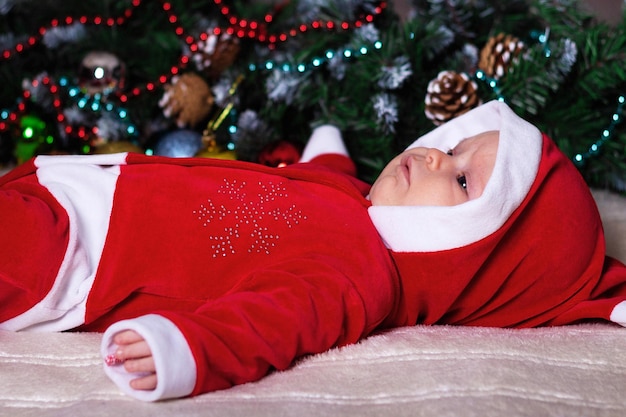 Little girl in Santa Claus costume lying on a blanket