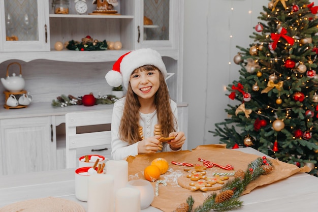 산타클로스 모자를 쓴 어린 소녀가 식탁에 앉아 있습니다.