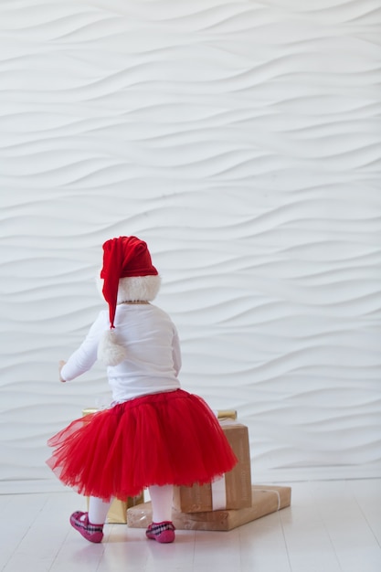 little girl in santa costume playing with holiday boxes