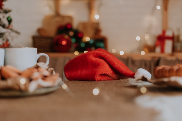 Little girl in Santa hat and a dwarf dachshund want to eat a plate of pastries and a Christmas cake