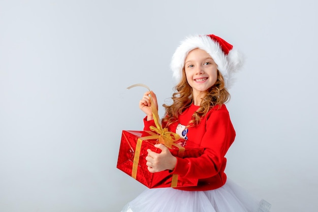Little girl in santa hat holds a gift on white background Christmas concept text space