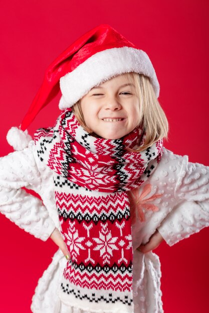 Little girl in santa hat and scarf on red