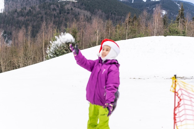 Bambina in cappello della santa con lo snowboard al resort invernale