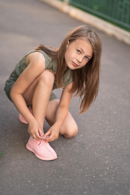 Маленькая девочка села завязывать шнурки на улице