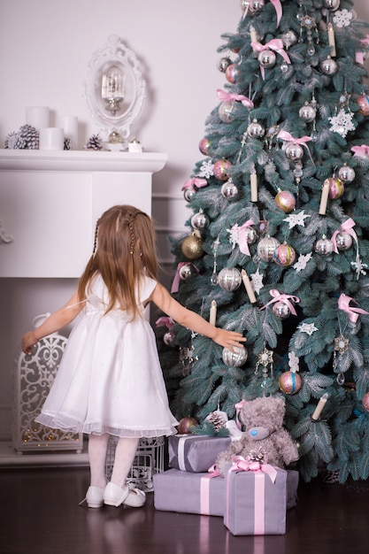 Little girl saw a mountain of gifts on which a teddy bear sits