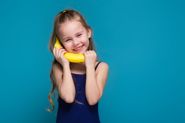 little girl in shirt with brunet hair hold a banana