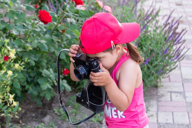 レトロな写真のカメラで花を撮影する少女をクローズアップ。