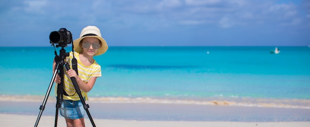 Little girl shooting with camera on tripod during her summer vacation