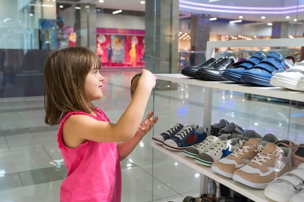 A little girl in a shopping center chooses shoes shopping