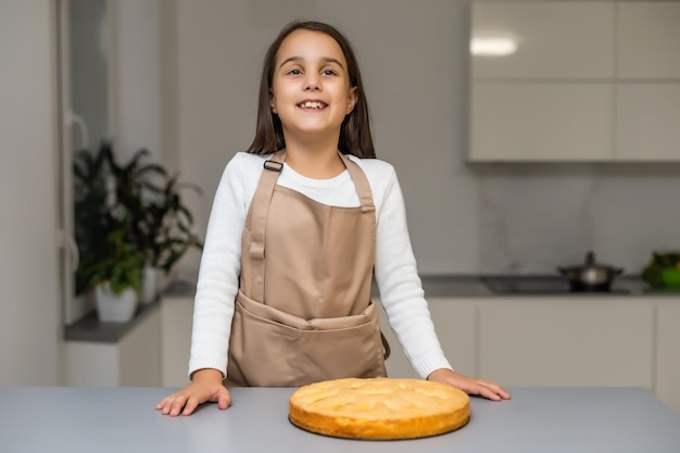 Bambina che mostra la torta di mele che ha cotto