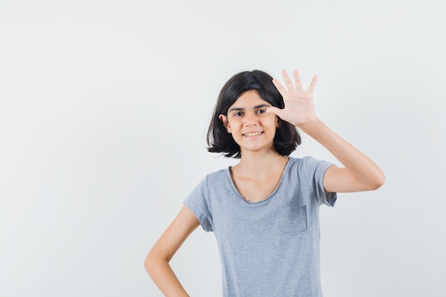 Little girl showing five fingers in t-shirt and looking confident , front view.