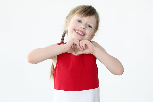 Bambina che mostra a forma di cuore con le sue mani