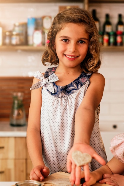 彼女のクッキーを見せている少女。幼児シェフのコンセプト。