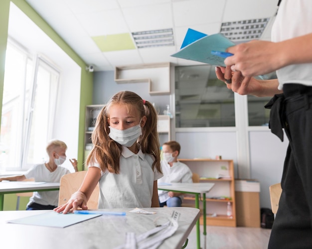 Little girl showing her homework to the teacher