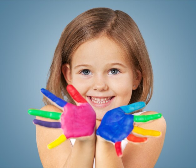 Little girl showing painted hands on studio background