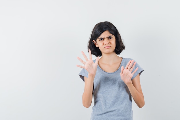 Little girl showing stop gesture in t-shirt and looking annoyed , front view.