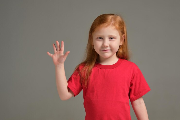 A little girl shows gesture - five fingers, isolated on grey background