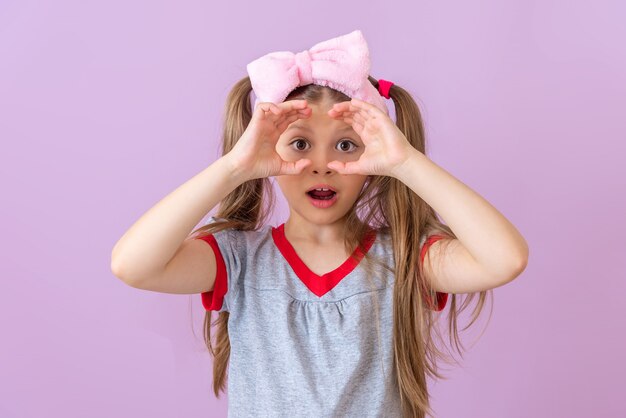 A little girl shows an imaginary pair of binoculars.